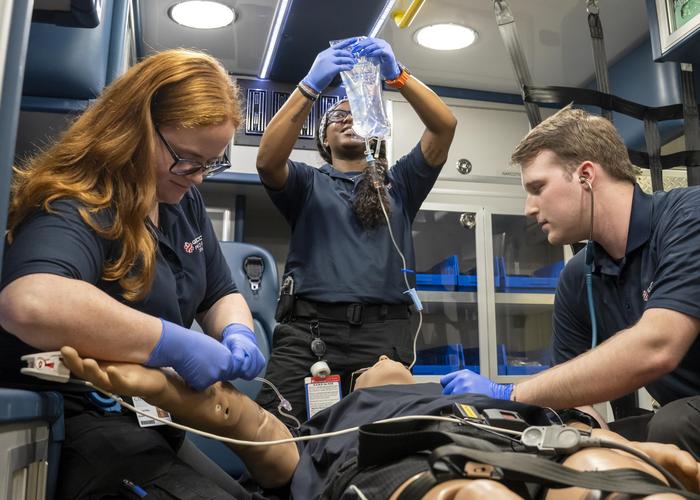 Three students practice treating a patient in an ambulance.